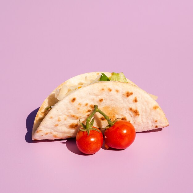 Arreglo con taco y tomates cherry sobre fondo morado