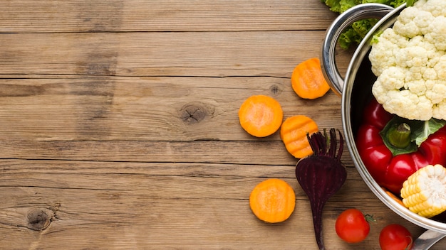 Arreglo de verduras coloridas sobre fondo de madera con espacio de copia