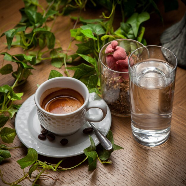 Desde arriba café expreso con agua y rama de uva y granos de café en taza