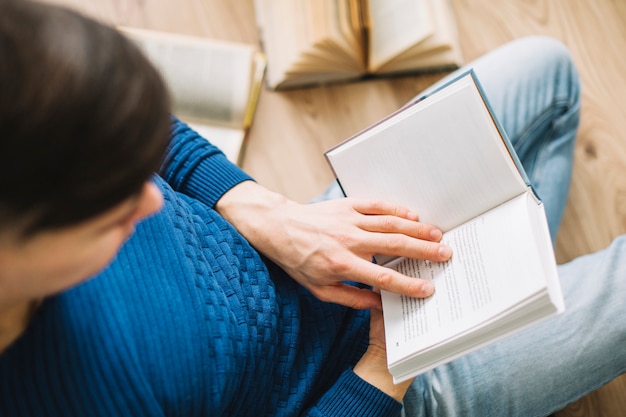 Desde arriba hombre descansando en el piso con el libro