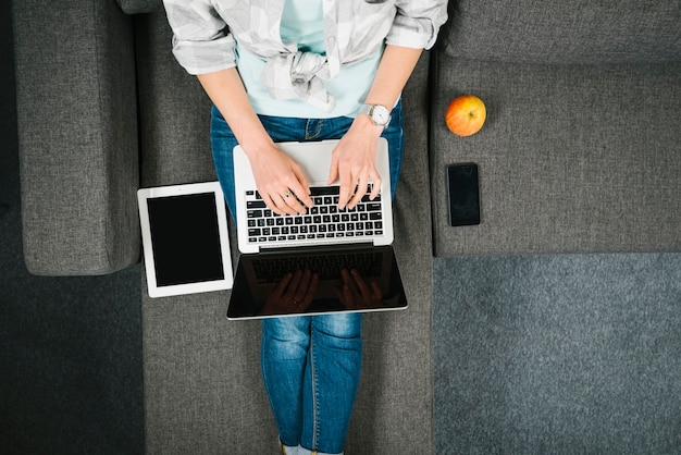 Desde arriba, la mujer busca la computadora portátil en el sofá