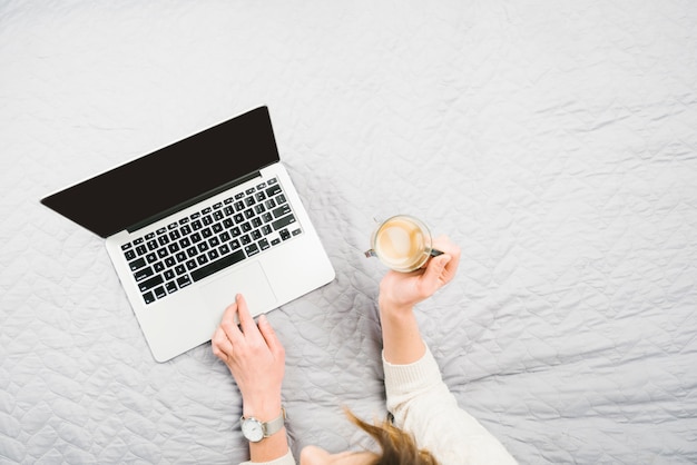 Foto gratuita desde arriba mujer con café acostado cerca de la computadora portátil