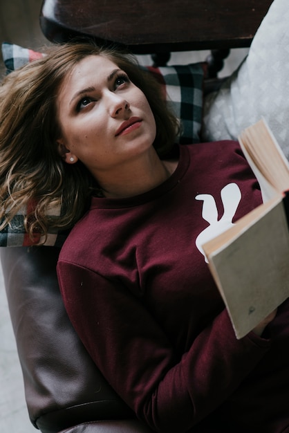 Desde arriba mujer con libro en sofá