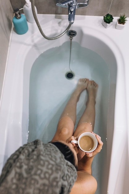 Desde arriba mujer tomando café en el baño