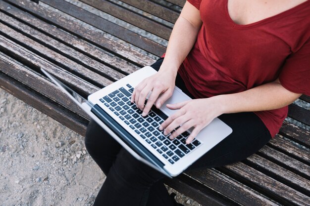 Desde arriba mujer usando laptop en banco