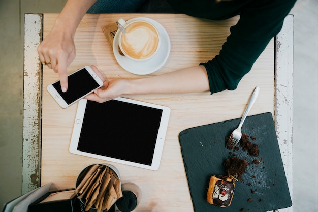 Foto gratuita desde arriba mujer usando teléfono inteligente en café