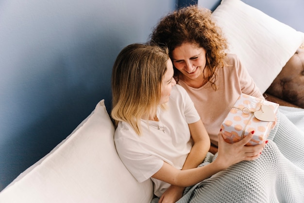 Desde arriba, mujeres intercambiando regalos en el sofá