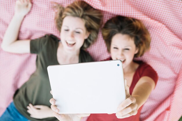 Desde arriba mujeres navegando tableta en picnic