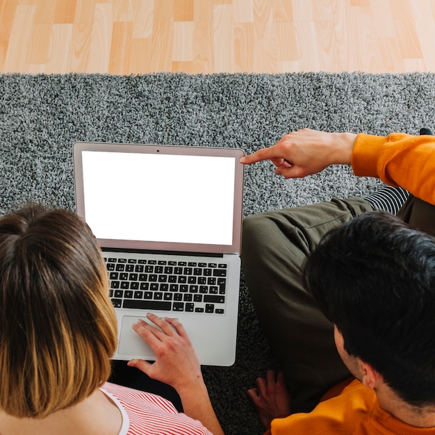 Desde arriba de la pareja usando la computadora portátil en el piso