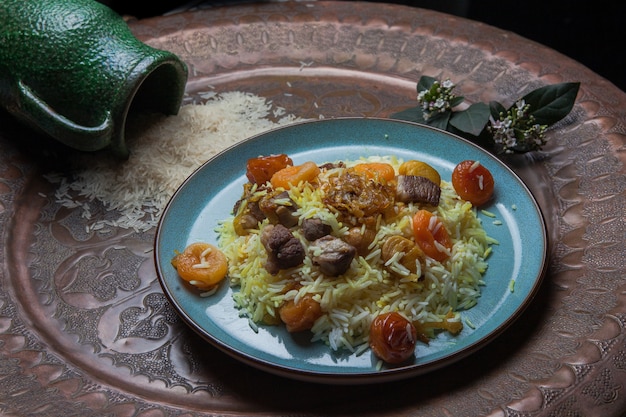 Desde arriba pilaf con frutas secas y secas y jarra en plato redondo