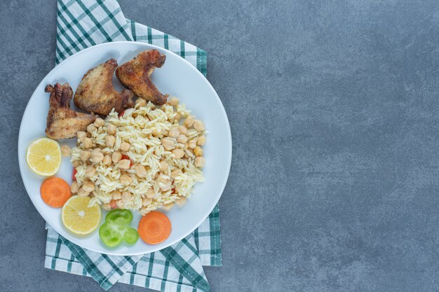 Arroz al vapor con garbanzos y alitas de pollo en un plato blanco.