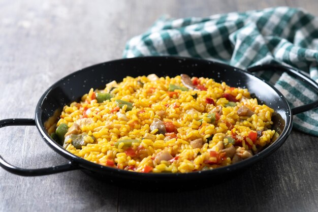 Arroz amarillo con pollo y verduras en una mesa de madera