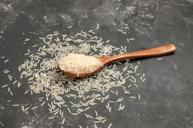 arroz arroz en la cuchara de madera sobre la mesa oscura
