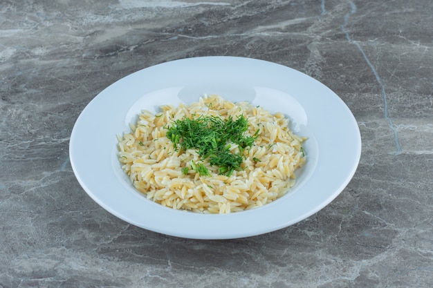 Arroz basmati cocido en un plato, sobre la mesa de mármol.