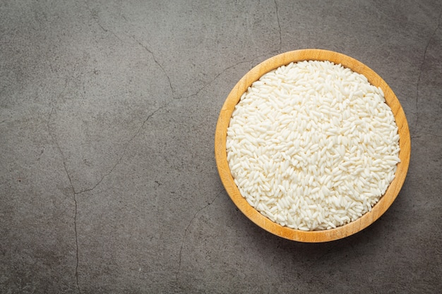 Arroz blanco en una pequeña placa de madera colocada en un piso oscuro