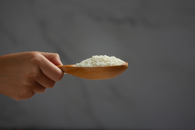 El arroz blanco se sostiene en una cuchara con la mano que sostiene la cuchara.