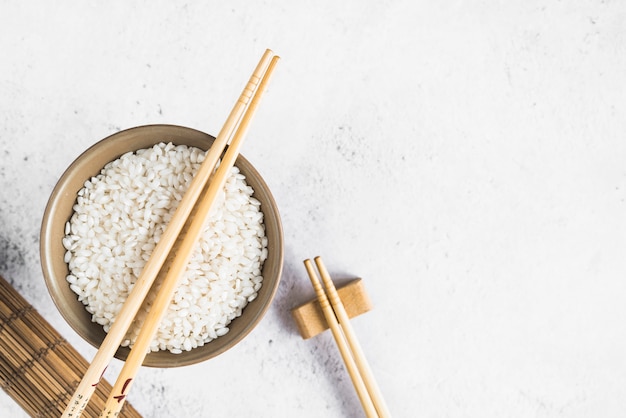 Arroz blanco en un tazón cerca de la estera de bambú