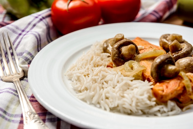 Foto gratuita arroz con carne y champiñones en plato blanco sobre tovel