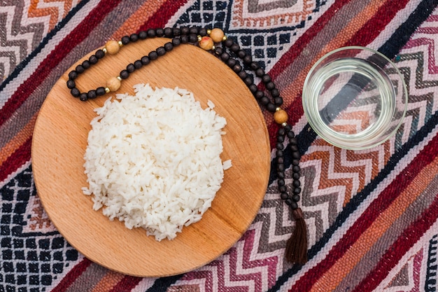 Arroz cocido sobre tabla de madera con cuentas.