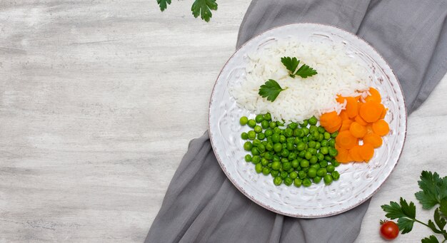 Arroz cocido con verduras y perejil en un plato sobre tela gris