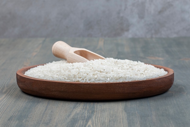 Arroz crudo saludable con cuchara de madera sobre una mesa de madera