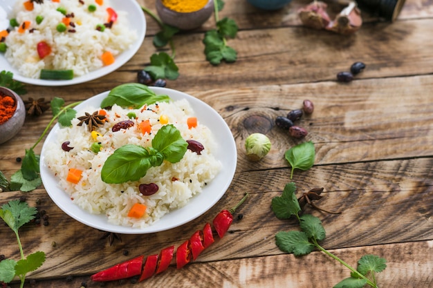 Arroz con frijoles y hojas de albahaca en un plato con ingredientes orgánicos en la mesa