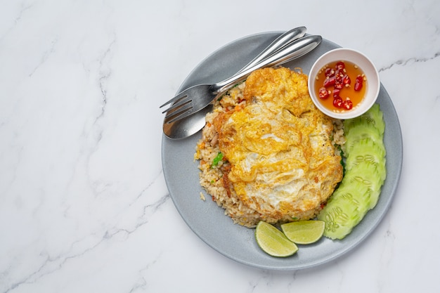 Arroz frito y huevo frito servido con salsa de pescado y pepino