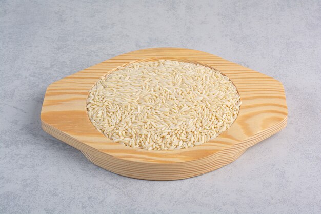 Arroz de grano corto y de grano largo apilado en bandejas junto a una fuente de trigo sarraceno sobre mármol.