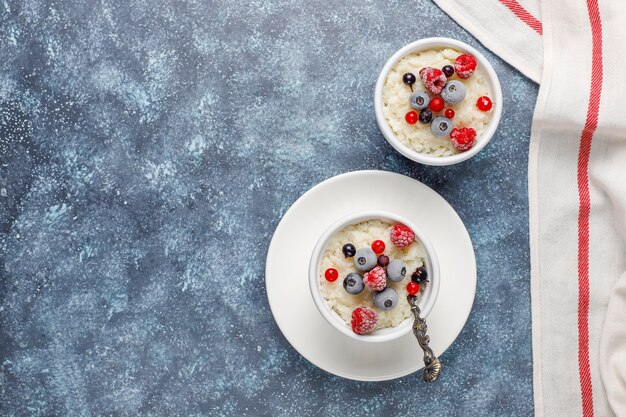 Arroz con leche con arándanos y frambuesas congelados en un tazón blanco