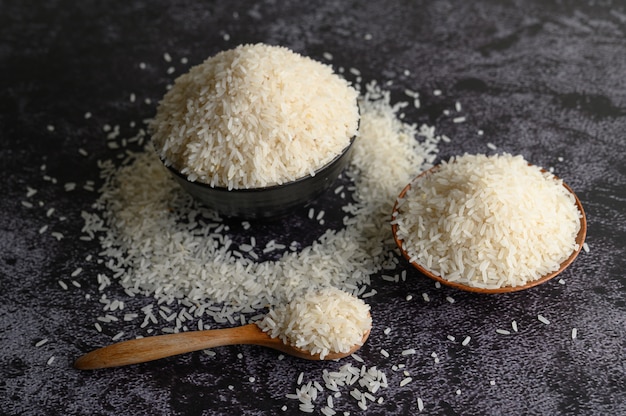 Arroz molido en un tazón y una cuchara de madera en el piso de cemento negro.