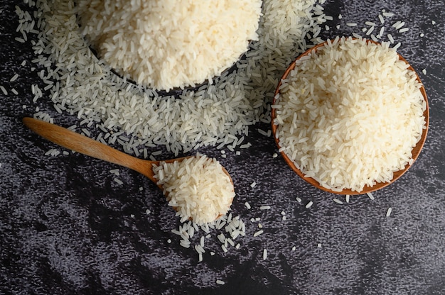 Arroz molido en un tazón y una cuchara de madera en el piso de cemento negro.