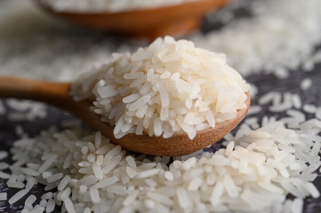 Arroz molido en un tazón y una cuchara de madera en el piso de cemento negro.