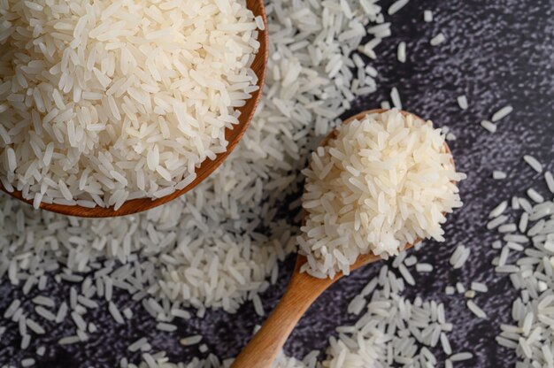 Arroz molido en un tazón y una cuchara de madera en el piso de cemento negro.