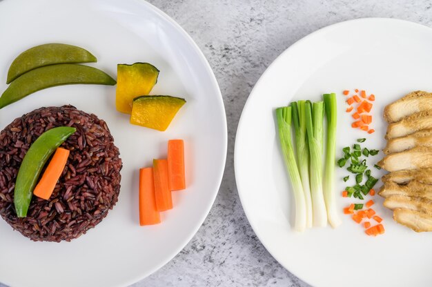 Arroz negro en un plato con calabaza, guisantes, zanahorias, elote y pechuga de pollo al vapor.