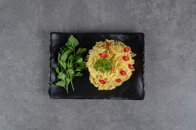 Arroz con rodajas de pimiento y verduras en placa negra. Foto de alta calidad