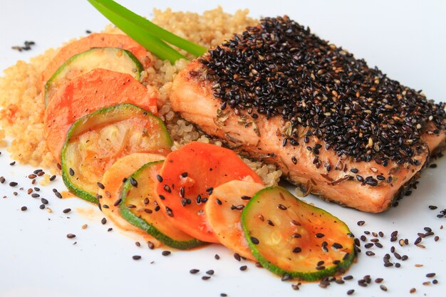 Arroz, salmón y verduras decoradas con semillas de chía servidas en un plato blanco