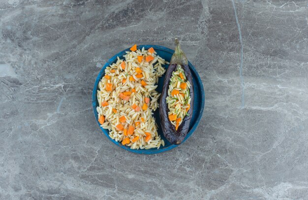 Arroz vegetariano en berenjena, en el plato, sobre la mesa de mármol.