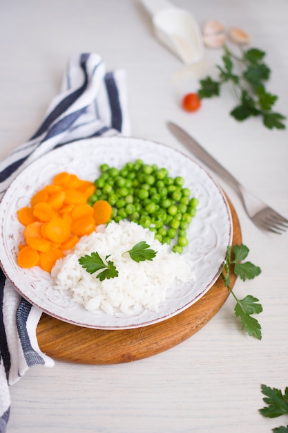 Arroz con verduras y perejil en tabla de madera cerca de servilleta y tenedor