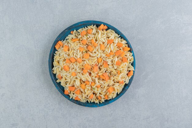 Arroz de zanahoria en el plato de madera, sobre el mármol.