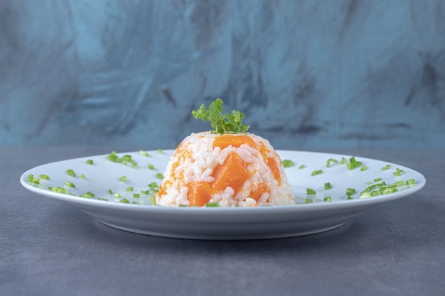 Foto gratuita arroz de zanahoria en el plato, sobre la superficie de mármol.