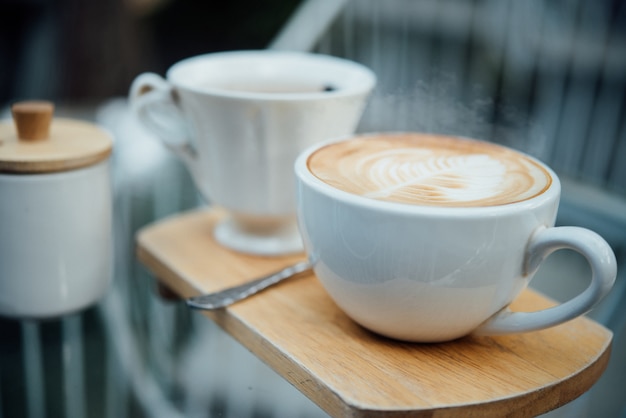 Arte caliente del latte en taza de café en la tabla de madera en cafetería