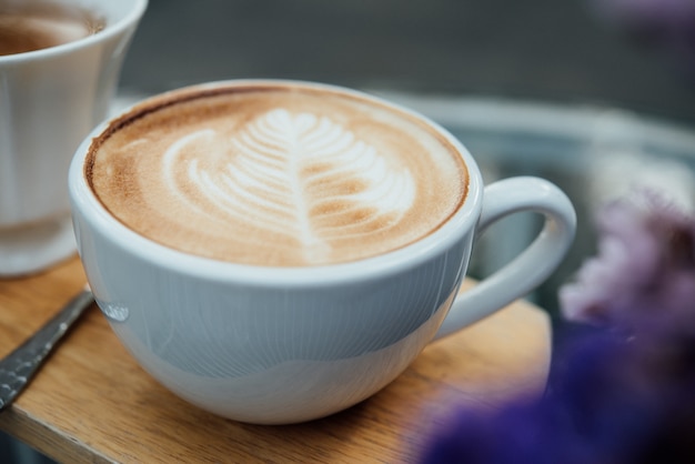 Arte caliente del latte en taza de café en la tabla de madera en cafetería