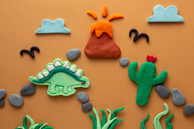 Arte de plastilina con dinosaurio y volcán.