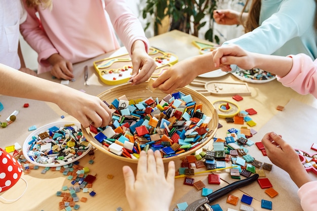 arte de rompecabezas de mosaico para niños, juego creativo para niños. las manos están jugando mosaico en la mesa. Detalles multicolores coloridos de cerca.