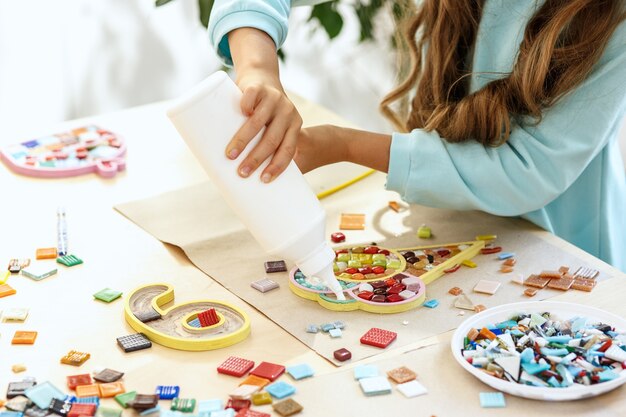 arte de rompecabezas de mosaico para niños, juego creativo para niños. las manos están jugando mosaico en la mesa. Detalles multicolores coloridos de cerca.