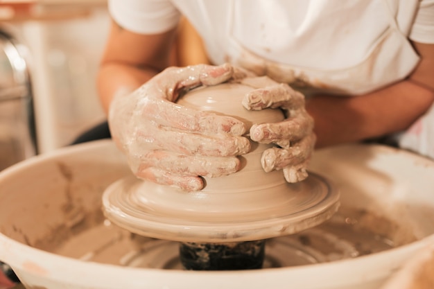 Artesana creando cerámica trabajando en la rueda formando arcilla.