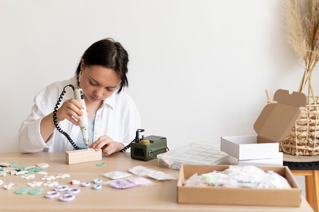 Artesana trabajando en el atelier con pistola de pegamento