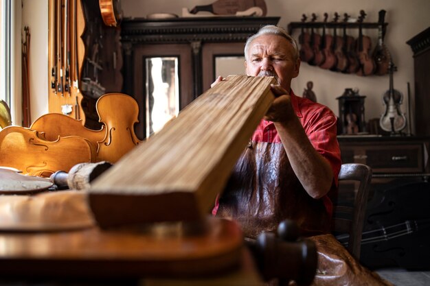 Artesano carpintero senior comprobando la calidad de la plancha de madera antes del trabajo