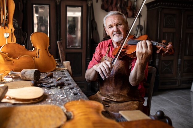 Artesano comprobando la calidad y tocando el violín en su antiguo taller de carpintero