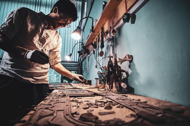 El artesano diligente está restaurando antiguas vidrieras rotas en su propio taller.